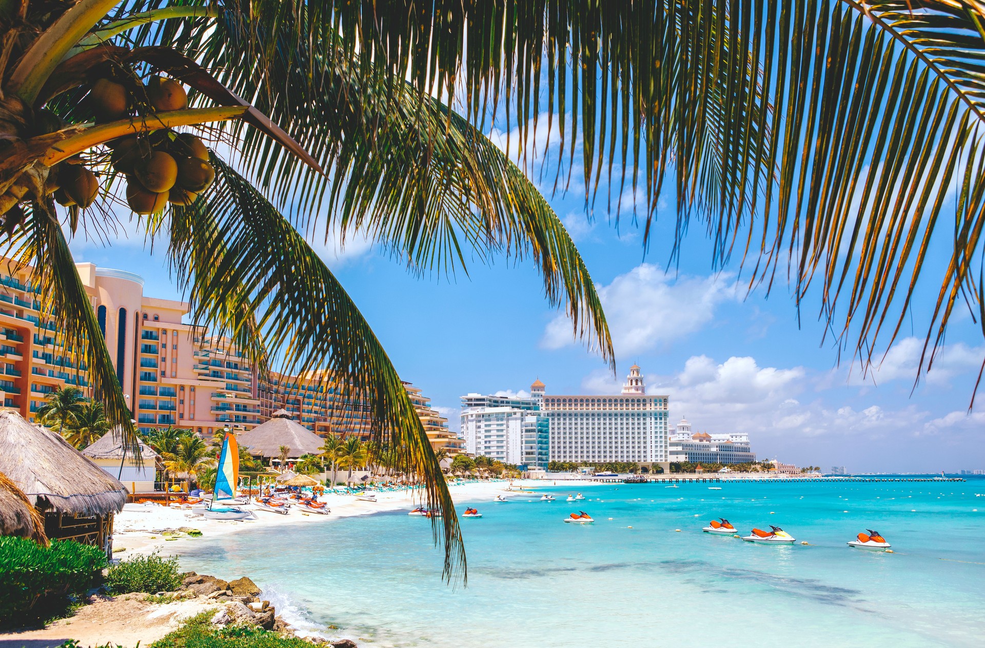 Cancun beach with hotels and plam tree in foreground