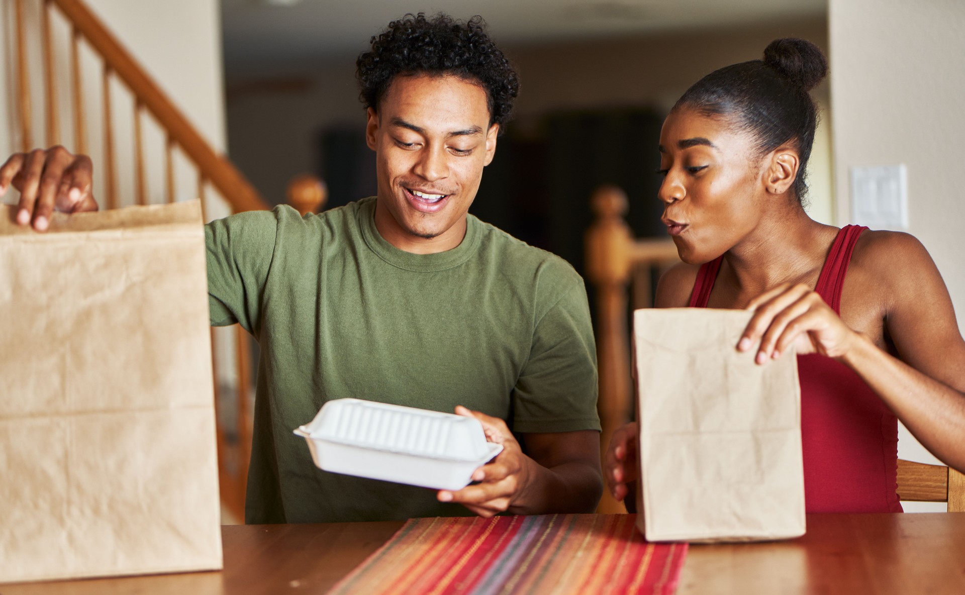 african american couple sitting at table looking at food delivery